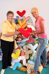 Viele Stunden Arbeit stecken in dem meterhohen Berg aus Herzkissen, die Barbara Wiest (links) ehrenamtlich genäht hat. Die kunterbunten Exemplare wird Fachkrankenschwester Petra Schäfer vom Klinikum Memmingen (rechts) an Brustkrebspatientinnen verteilen. Foto: Häfele/Pressestelle Klinikum Memmingen
