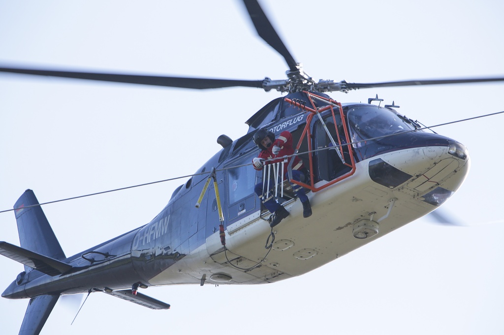Nur für Schwindelfreie: Die Montage der Marker erfolgt von einer seitlich an einem Helikopter angebrachten Plattform. Foto: LEW/Sanz